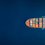 Aerial top down view of a large container cargo ship in motion over open ocean with copy space